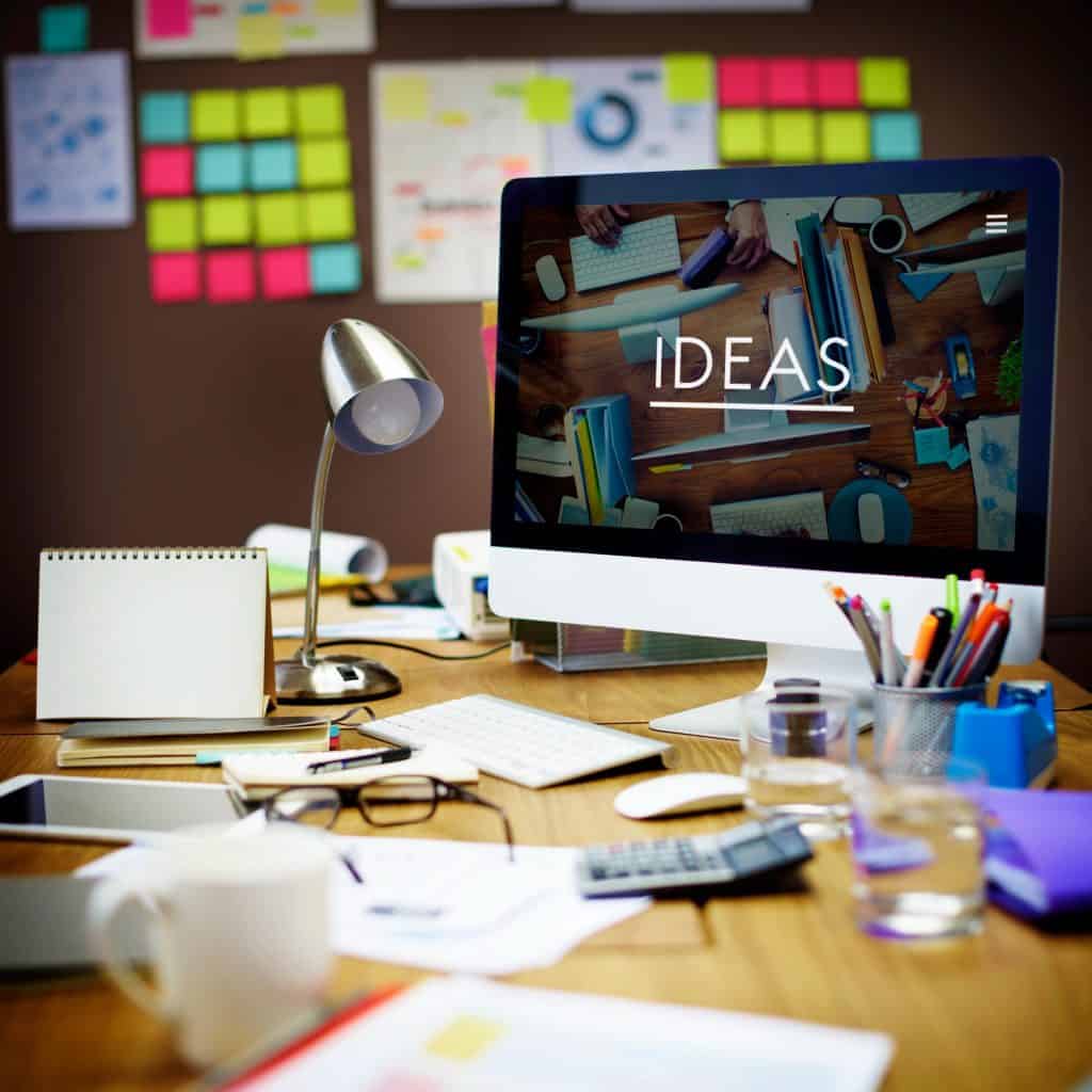 Overhead view of a creative web designer’s desk with a computer showing the word Ideas on screen, used for ecommerce website design in Leeds.